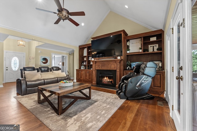 living room featuring hardwood / wood-style flooring, high vaulted ceiling, crown molding, and ceiling fan with notable chandelier