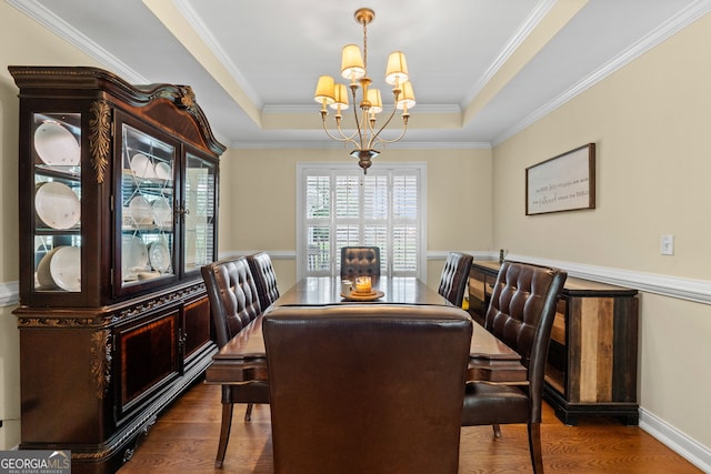 dining area featuring crown molding, dark hardwood / wood-style floors, a raised ceiling, and an inviting chandelier