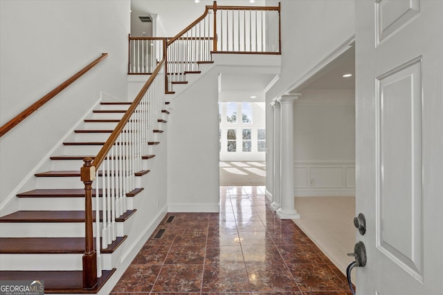 stairs featuring decorative columns and a high ceiling