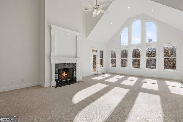 carpeted living room with a fireplace, a towering ceiling, and ceiling fan