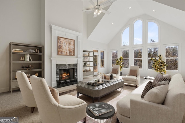 carpeted living room featuring a high end fireplace, a high ceiling, and ceiling fan