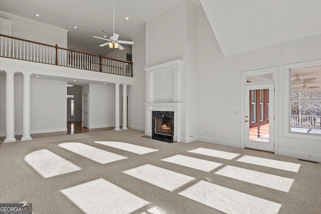 unfurnished living room featuring carpet floors, a premium fireplace, high vaulted ceiling, and ceiling fan