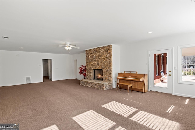 unfurnished living room with carpet, ceiling fan, and a stone fireplace