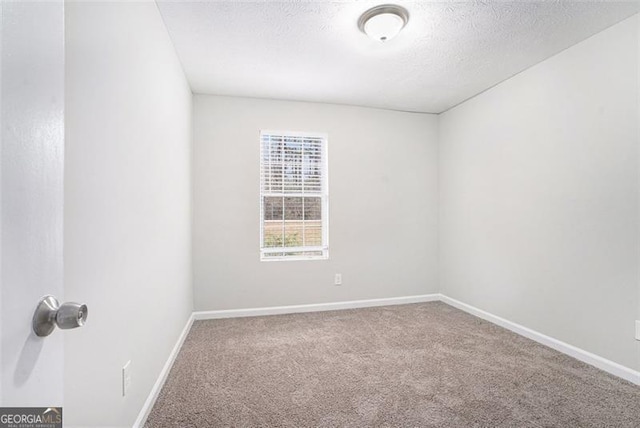 carpeted empty room featuring a textured ceiling