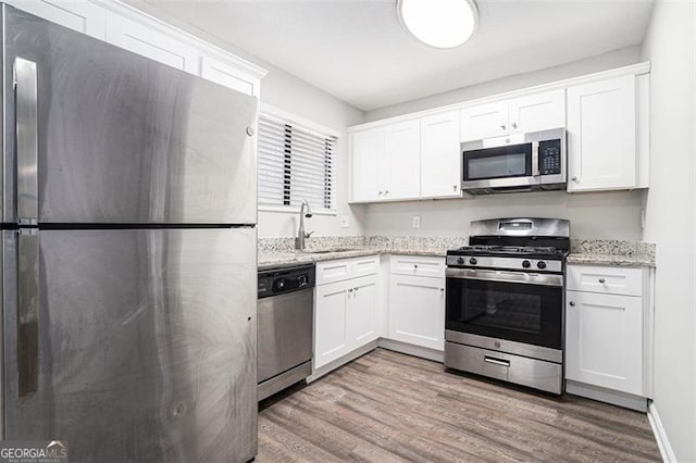 kitchen with light stone counters, sink, white cabinets, and appliances with stainless steel finishes