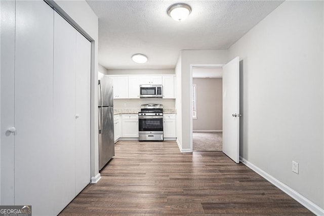 kitchen with dark hardwood / wood-style floors, white cabinetry, a textured ceiling, and appliances with stainless steel finishes