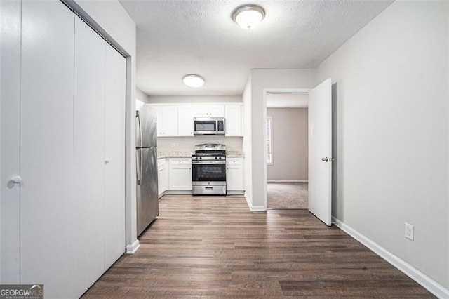 kitchen with white cabinets, dark hardwood / wood-style floors, a textured ceiling, and appliances with stainless steel finishes