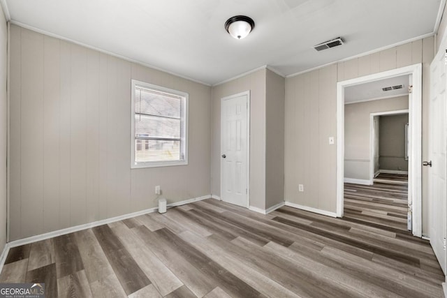 empty room with wood-type flooring and crown molding