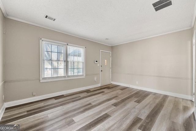 empty room featuring wood-type flooring, a textured ceiling, and ornamental molding