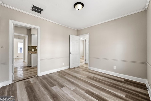 unfurnished bedroom featuring crown molding and light hardwood / wood-style floors