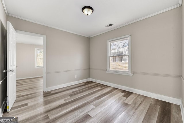 spare room with a wealth of natural light, light hardwood / wood-style floors, and ornamental molding