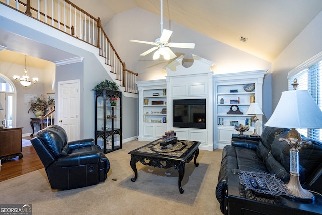 living room with ceiling fan with notable chandelier, crown molding, a towering ceiling, and light carpet