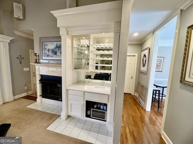 bar featuring crown molding, sink, white cabinets, and light colored carpet