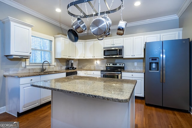 kitchen with light stone countertops, sink, a kitchen island, white cabinets, and appliances with stainless steel finishes