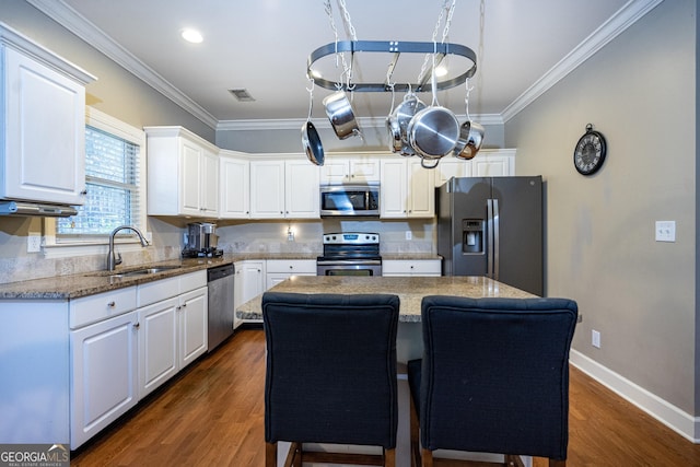 kitchen featuring appliances with stainless steel finishes, dark wood-type flooring, sink, white cabinets, and a center island