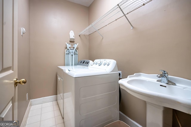 washroom with washer and clothes dryer, light tile patterned floors, and sink