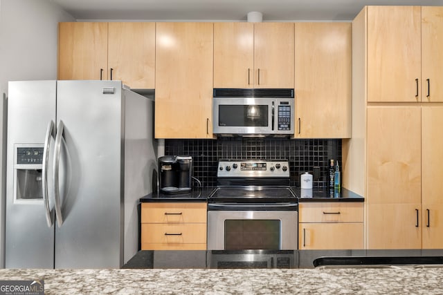 kitchen with appliances with stainless steel finishes, light brown cabinets, and dark stone countertops