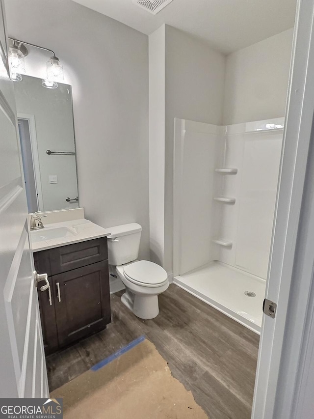 bathroom featuring hardwood / wood-style floors, vanity, toilet, and walk in shower