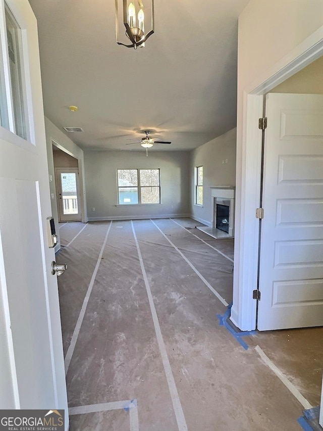 unfurnished living room with ceiling fan with notable chandelier