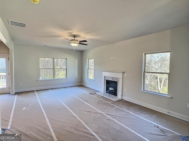 unfurnished living room featuring a fireplace, ceiling fan, and plenty of natural light