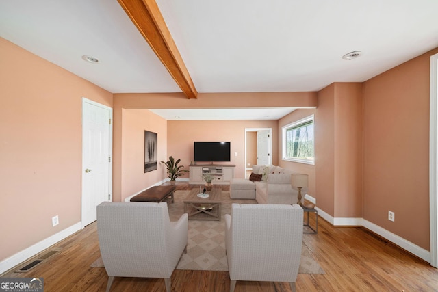 living room featuring beamed ceiling and light hardwood / wood-style flooring