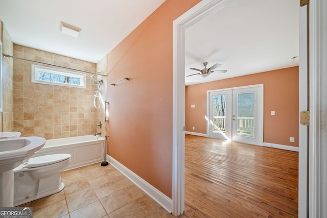 bathroom featuring french doors, ceiling fan, toilet, and tiled shower / bath combo