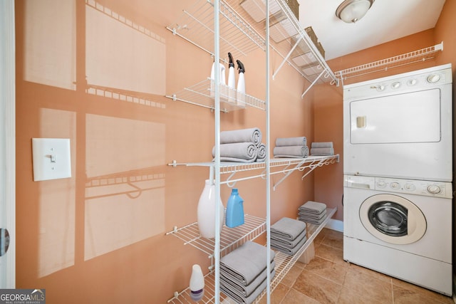 clothes washing area with stacked washer and dryer and tile patterned floors