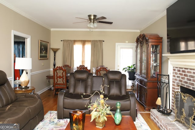 living room with a fireplace, light wood-type flooring, ceiling fan, and crown molding