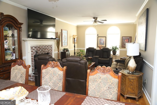 living room featuring ceiling fan, ornamental molding, dark wood-type flooring, and a brick fireplace