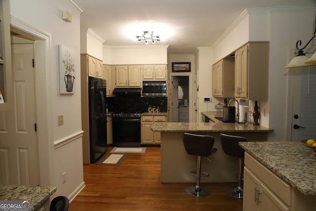 kitchen featuring stove, dark hardwood / wood-style flooring, tasteful backsplash, black fridge, and light stone counters