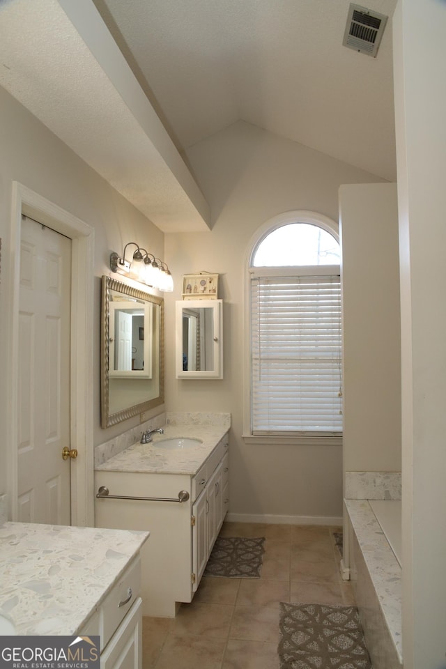 bathroom featuring tile patterned flooring, vanity, a bathing tub, and vaulted ceiling