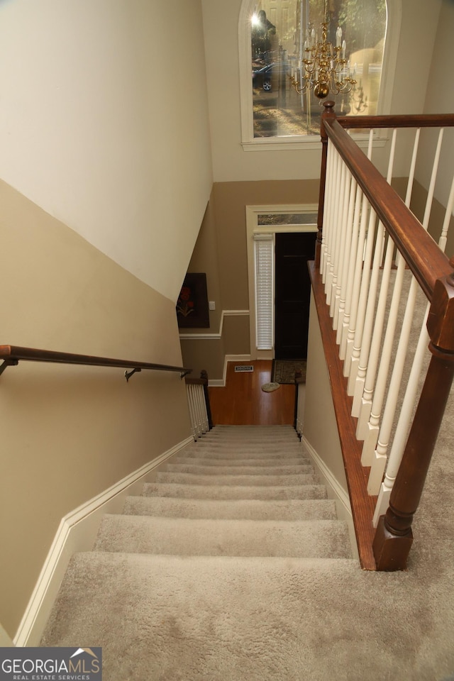 stairs featuring a notable chandelier