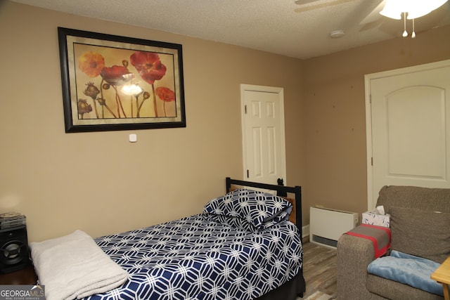 bedroom featuring ceiling fan, a textured ceiling, and hardwood / wood-style flooring