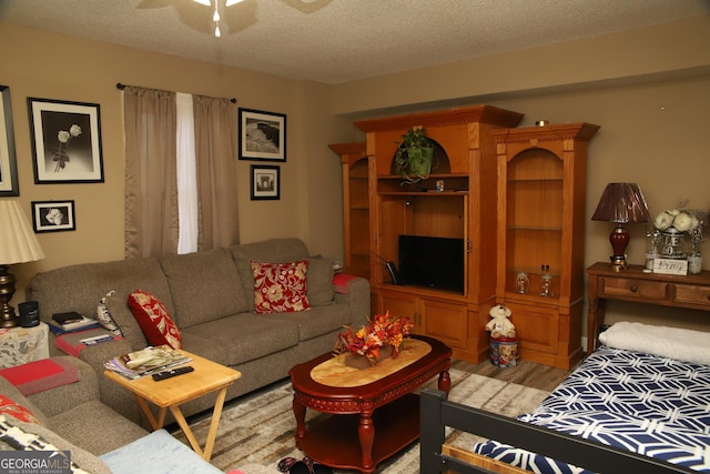 living room featuring ceiling fan, light hardwood / wood-style floors, and a textured ceiling