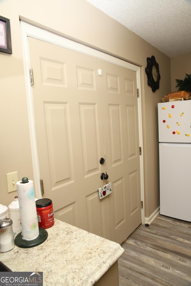 kitchen featuring a textured ceiling, white refrigerator, and hardwood / wood-style flooring