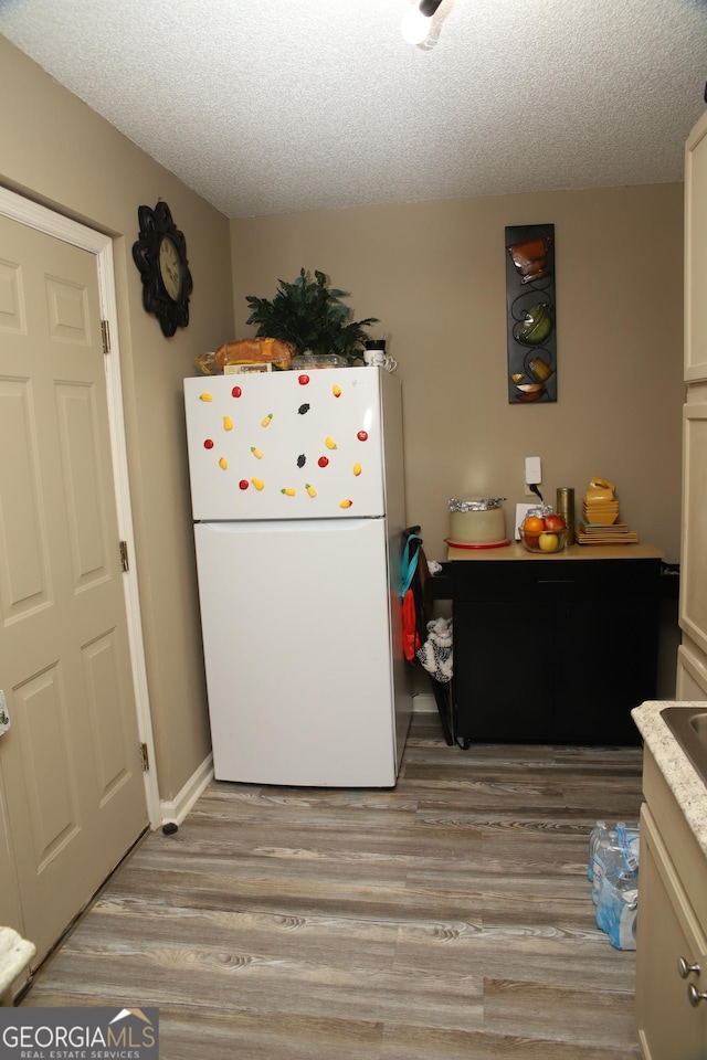 kitchen featuring light wood-type flooring, a textured ceiling, white fridge, and white cabinets