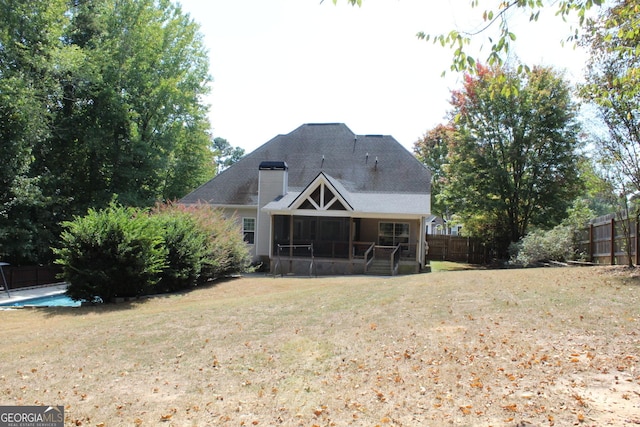 rear view of house featuring a lawn and a sunroom