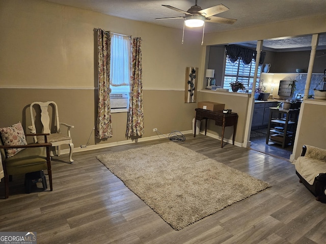 living area featuring ceiling fan, cooling unit, a textured ceiling, and hardwood / wood-style flooring