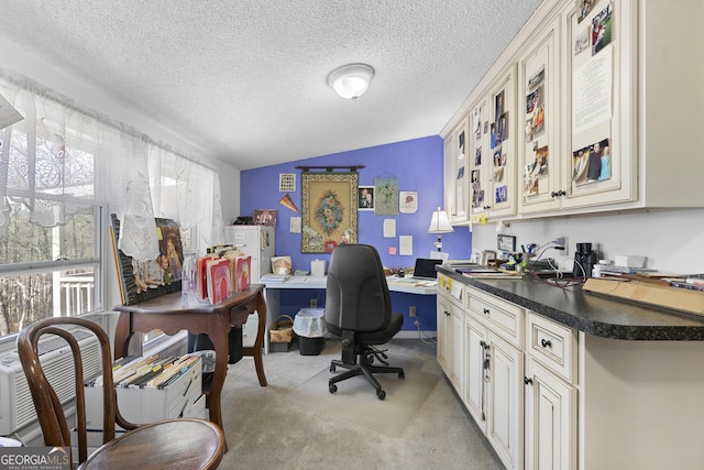 carpeted home office with a healthy amount of sunlight, built in desk, a textured ceiling, and lofted ceiling