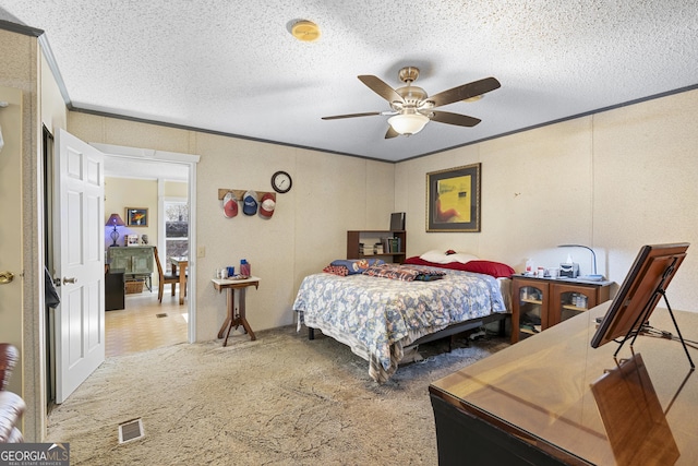 bedroom with a textured ceiling, ceiling fan, carpet floors, and crown molding