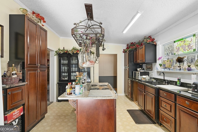 kitchen with crown molding, a center island, sink, and a textured ceiling