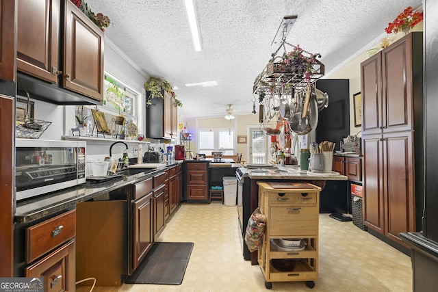 kitchen featuring crown molding, sink, ceiling fan, a textured ceiling, and a kitchen island