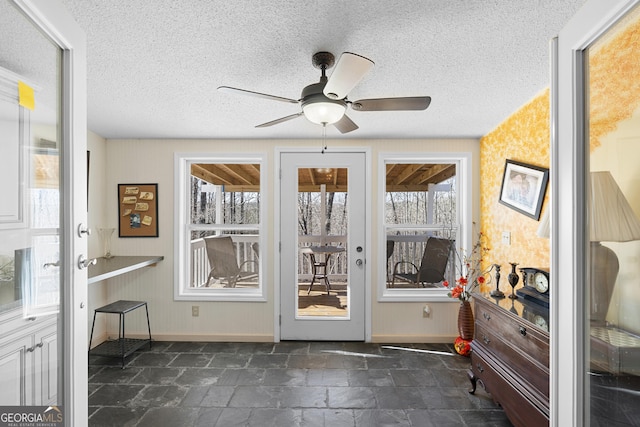 doorway featuring plenty of natural light, ceiling fan, and a textured ceiling