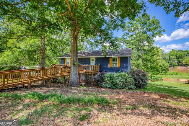 rear view of house featuring a lawn and a deck