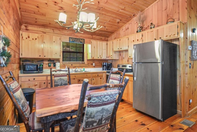 kitchen with stainless steel appliances, a chandelier, lofted ceiling, light brown cabinetry, and light wood-type flooring