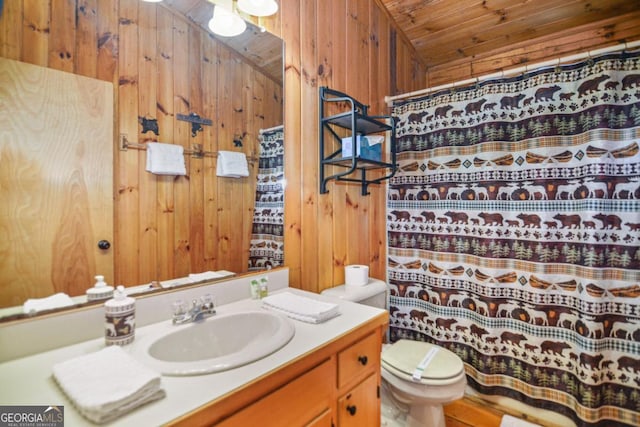 bathroom with vanity, toilet, wooden walls, and wood ceiling