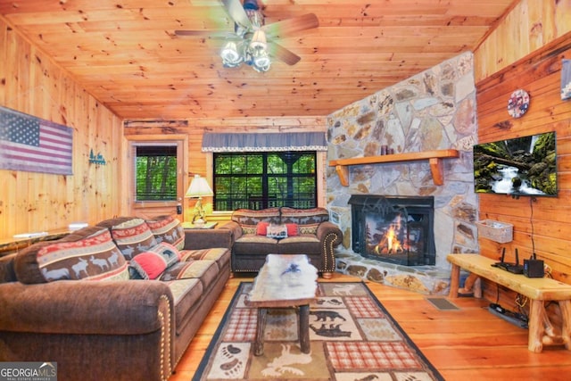 living room with hardwood / wood-style floors, wood walls, a fireplace, and wooden ceiling