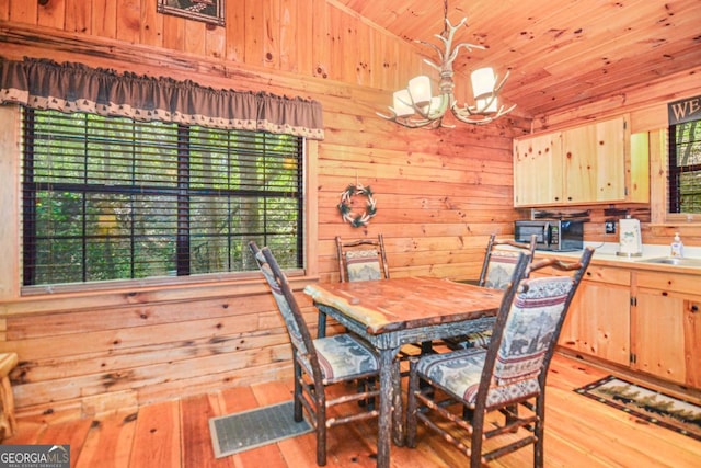 dining area featuring light hardwood / wood-style flooring, an inviting chandelier, wooden walls, and wood ceiling