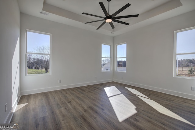 unfurnished room with a raised ceiling, ceiling fan, and dark hardwood / wood-style floors