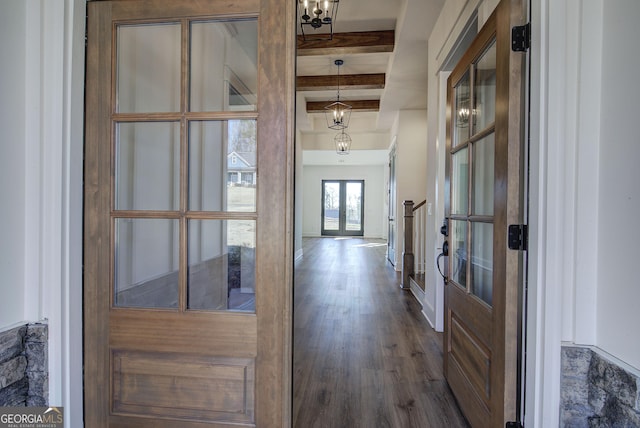 hallway with beamed ceiling, dark hardwood / wood-style floors, an inviting chandelier, and french doors